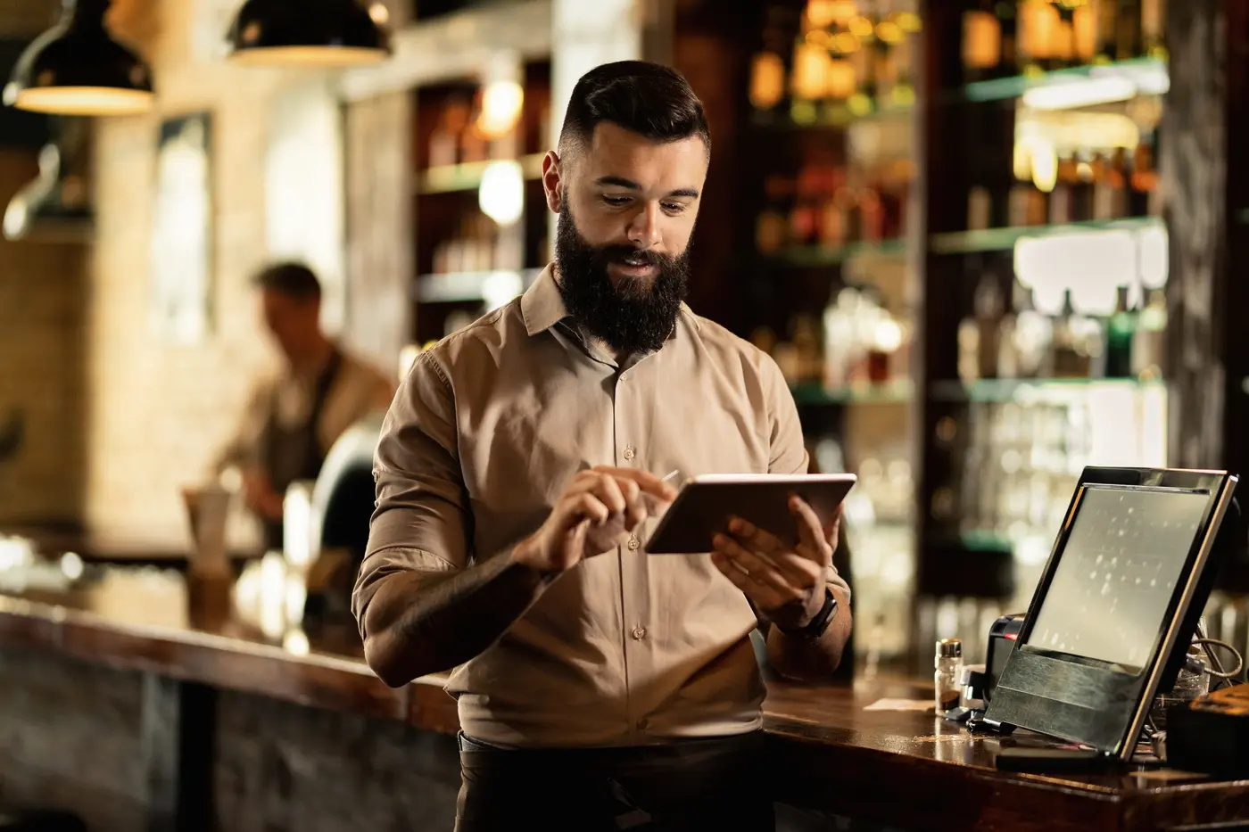 Un camarero consulta una tableta en la barra de su bar