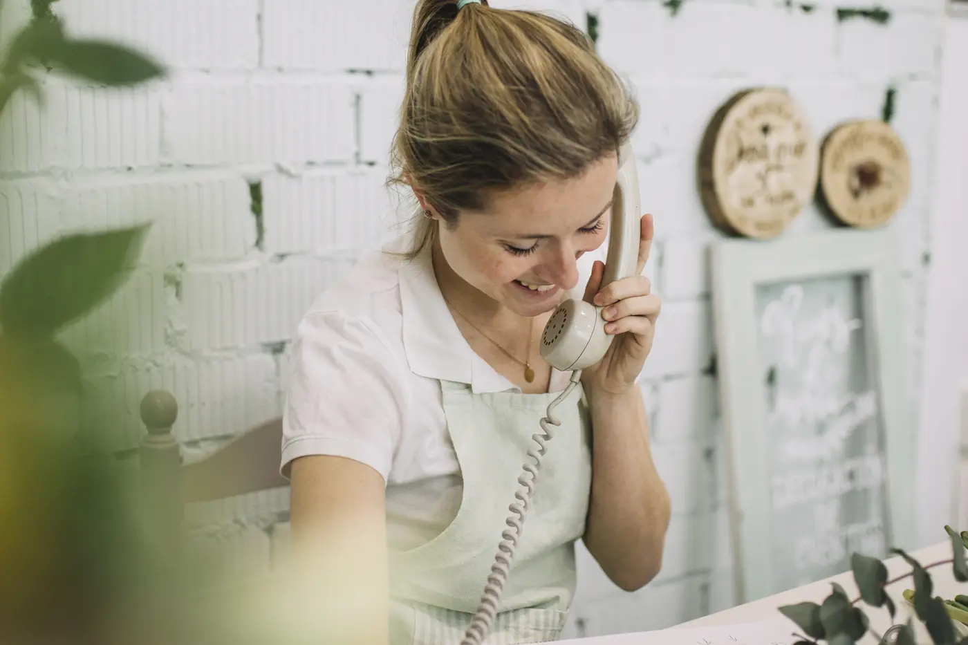 Una florista sonríe mientras habla por teléfono con un cliente